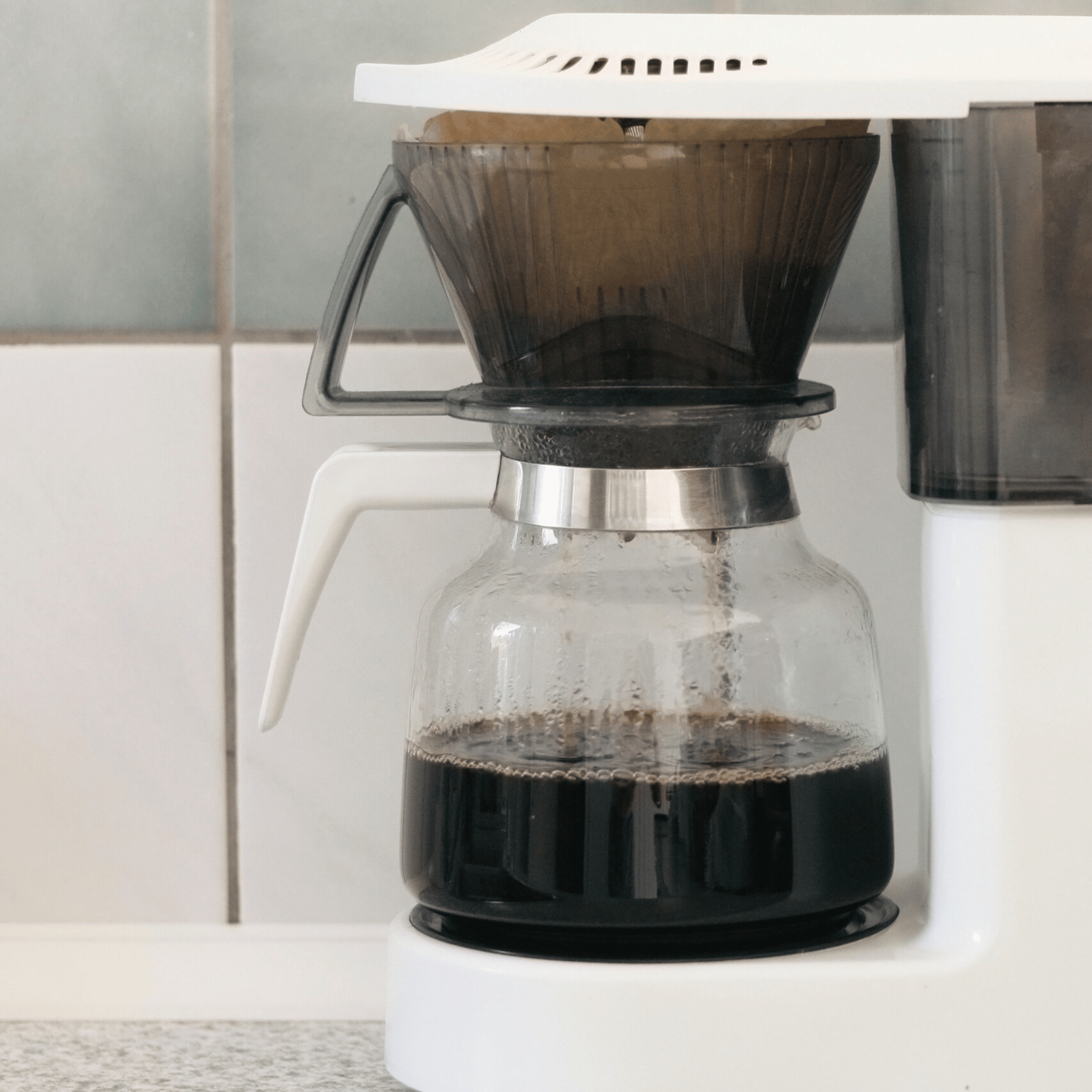 Filterkaffe brygges på kaffemaskine med friskkværnet kaffe og papirfilter for en ren og balanceret kop.