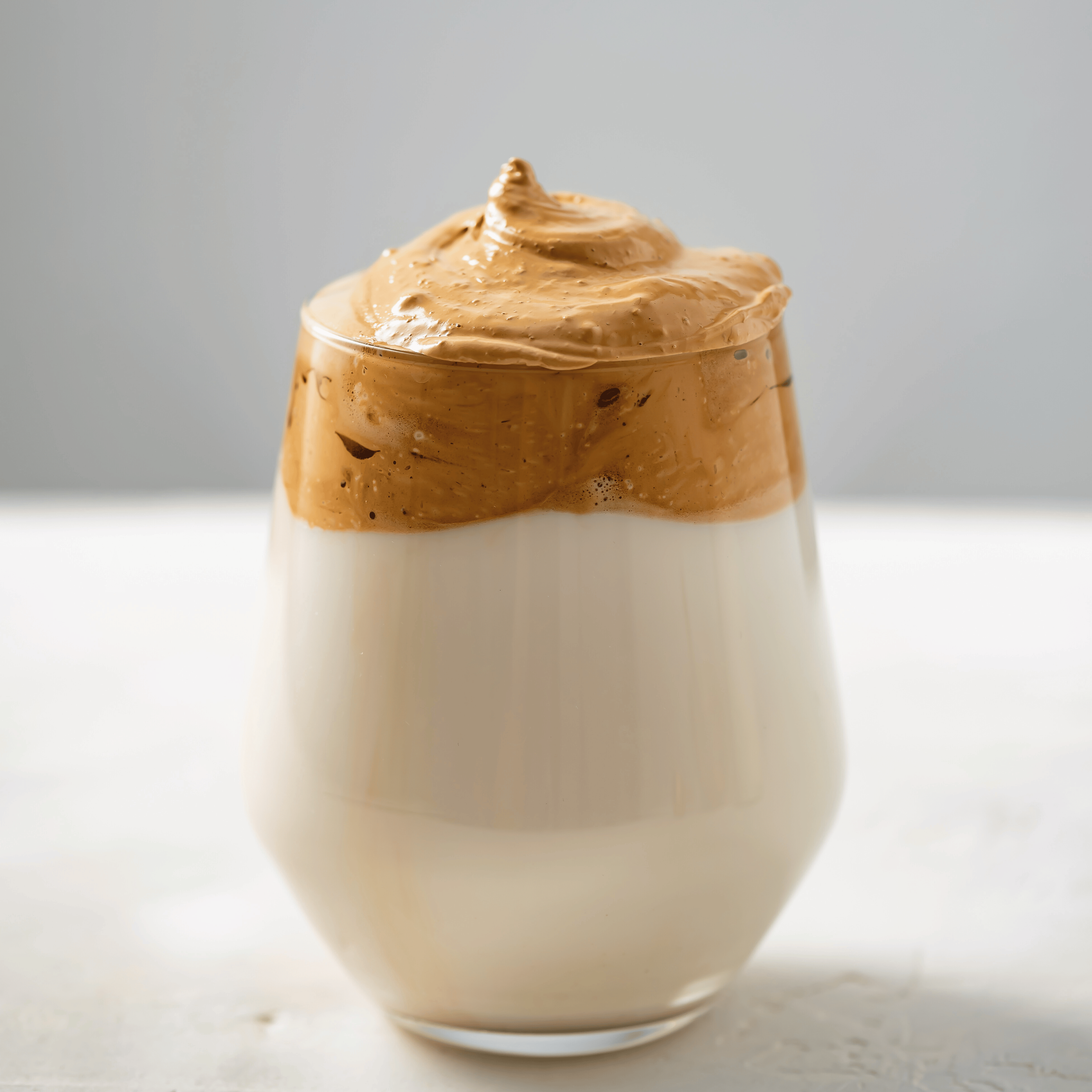 Cremet dalgona coffee med luftigt kaffeskum ovenpå kold mælk i glas